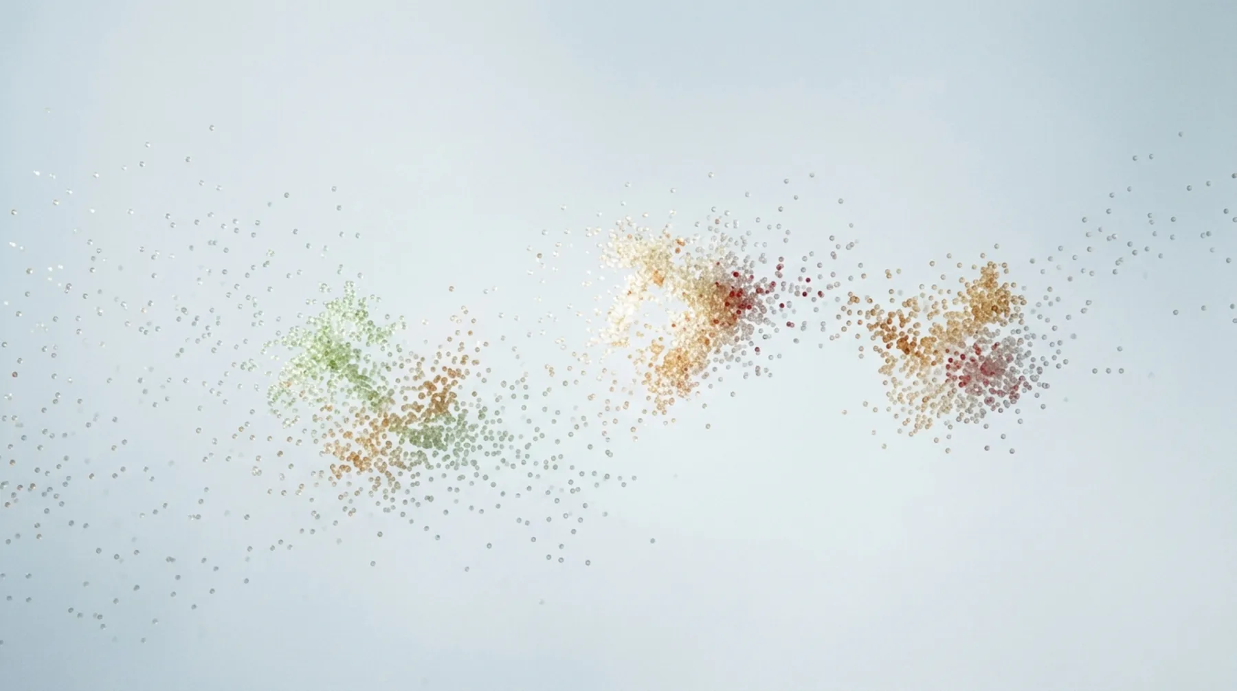 Feine farbige Punktwolken in Grün, Gelb und Rot auf hellem Grund.