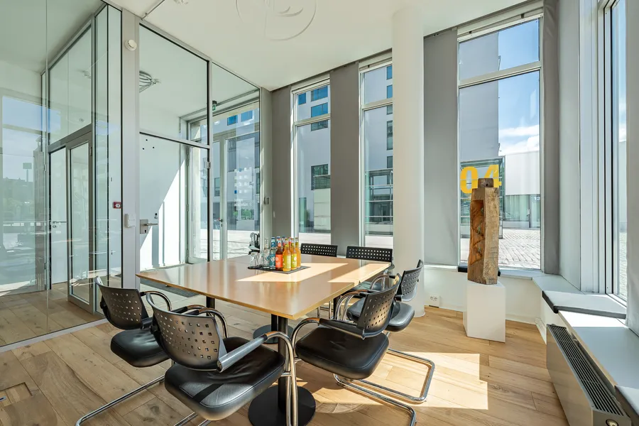 Kleiner Besprechungsraum des Instituts mit Holztisch, sechs Freischwingern und bodentiefen Fenstern zum Hof des Rheinauhafens.